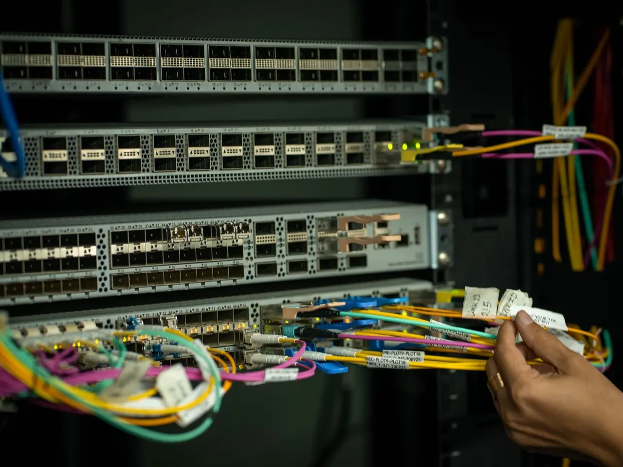 Handen van een technicus met glasvezel-patchkabels bij een verdeelpaneel